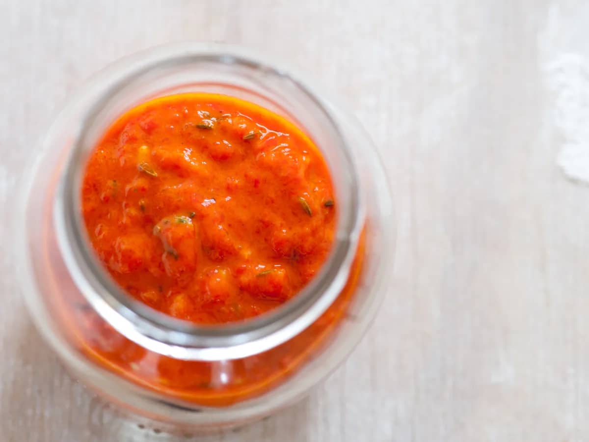 Bright red harissa chili paste in a glass jar
