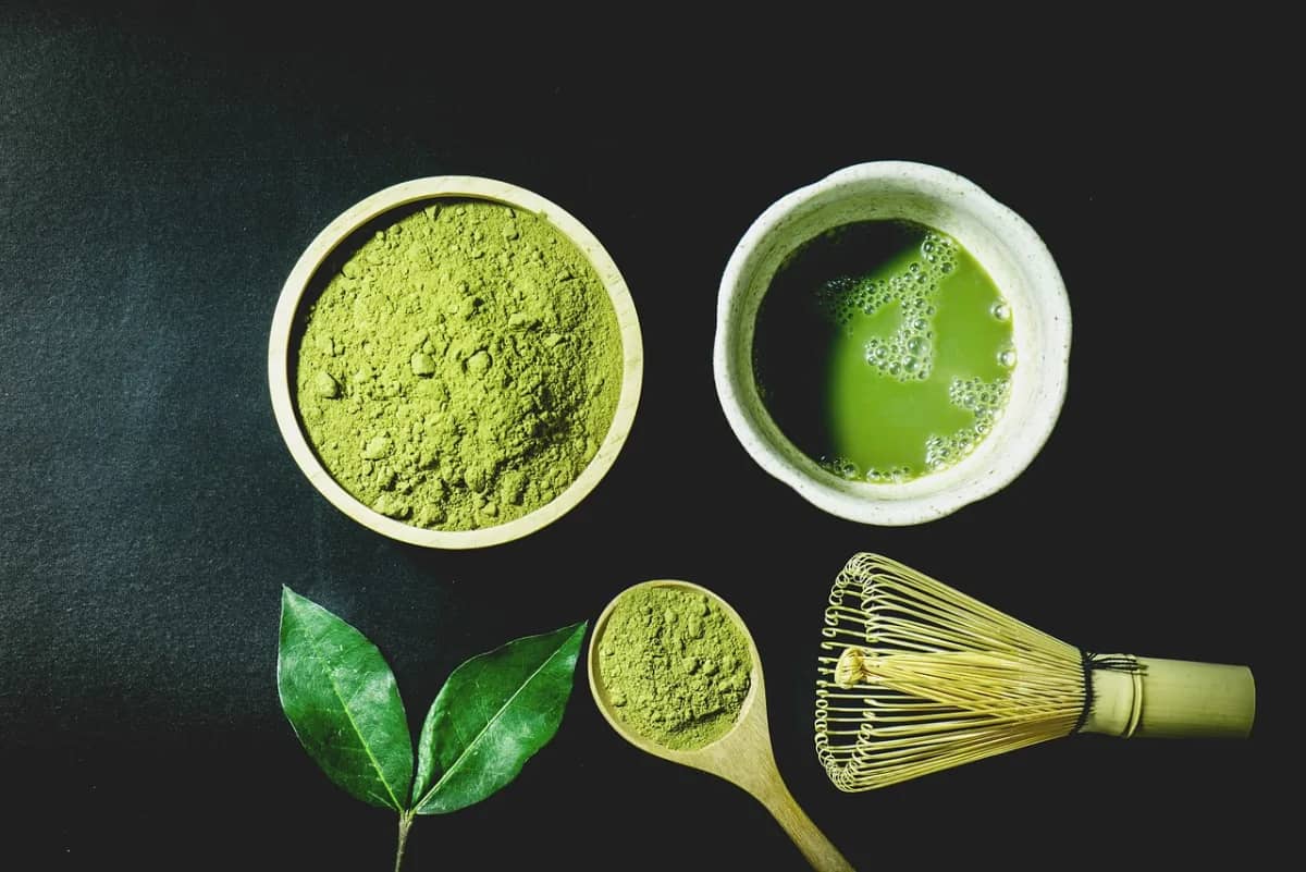 Bright green matcha powder with a bamboo whisk and tea bowl