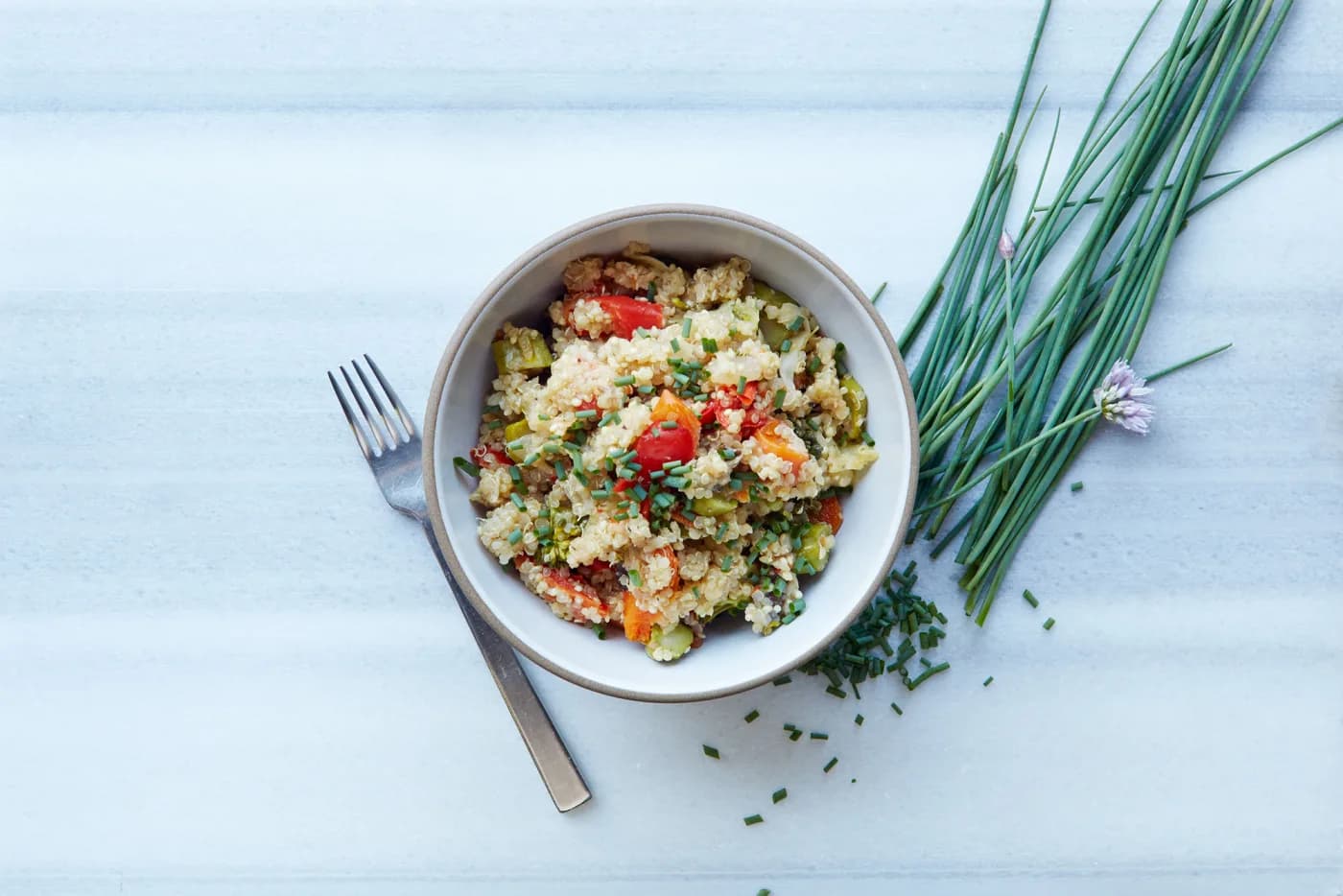 Bowl of cooked quinoa with vegetables and chives