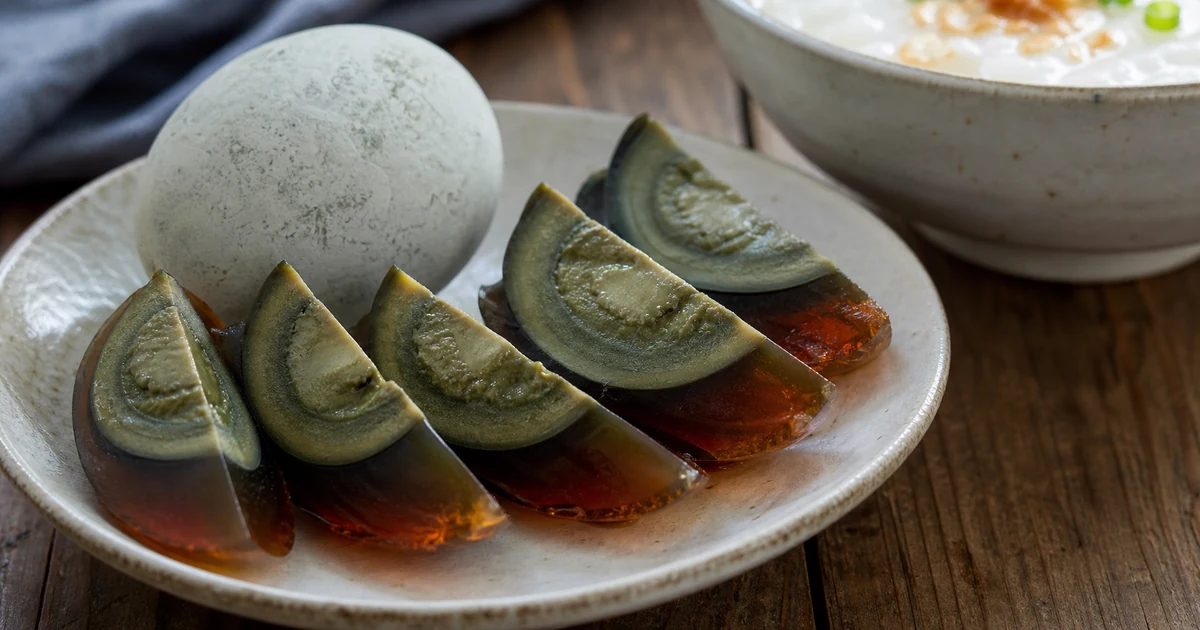 Sliced translucent century eggs with dark green yolks on a Chinese ceramic plate