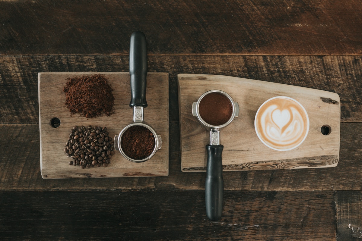 Black coffee in a cup on a wooden table with scattered roasted beans