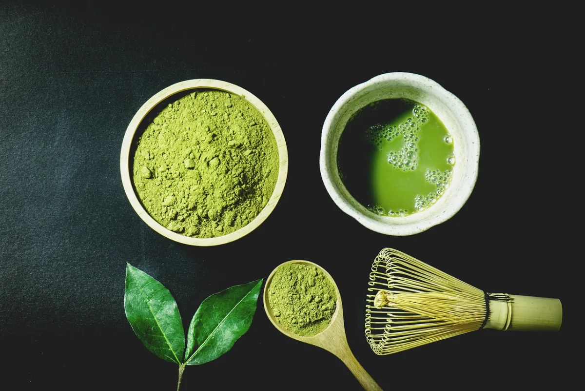 Bright green matcha powder with a bamboo whisk and tea bowl