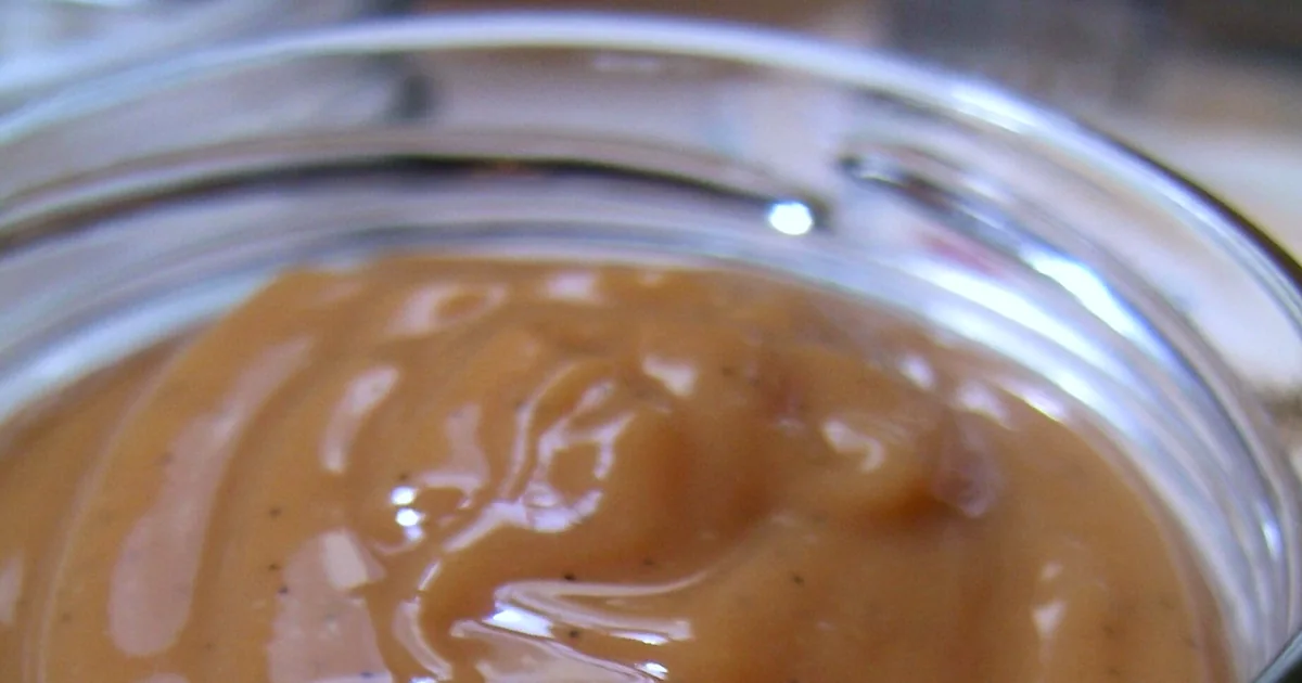 Glossy dulce de leche beside milk, sugar, pastries, and a wooden spoon