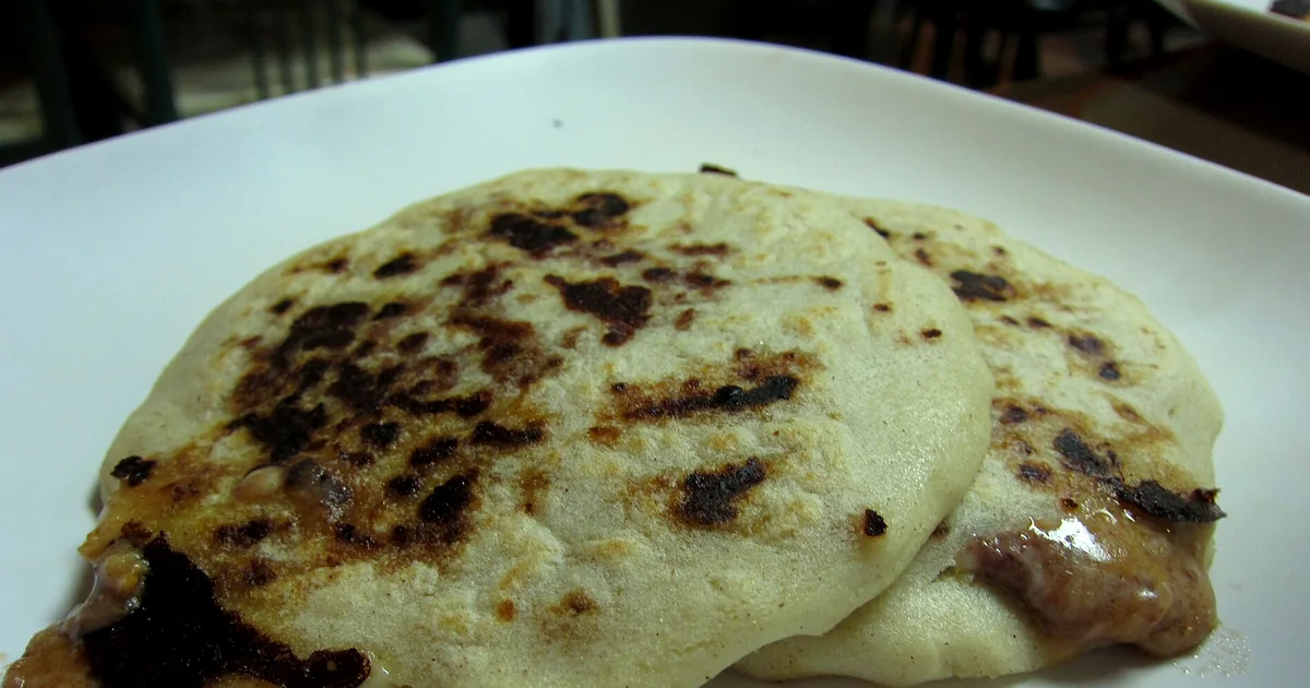 Salvadoran pupusas with cheese and beans beside curtido and tomato sauce