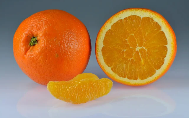 Whole and sliced sweet oranges with bright orange peel
