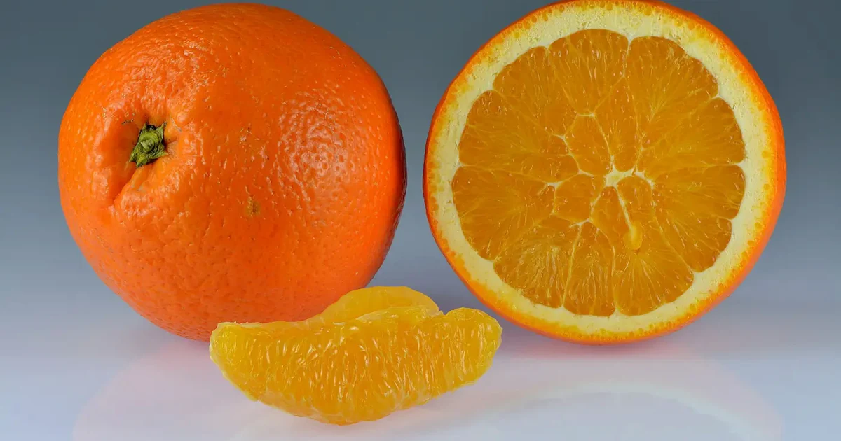 Whole and sliced sweet oranges with bright orange peel